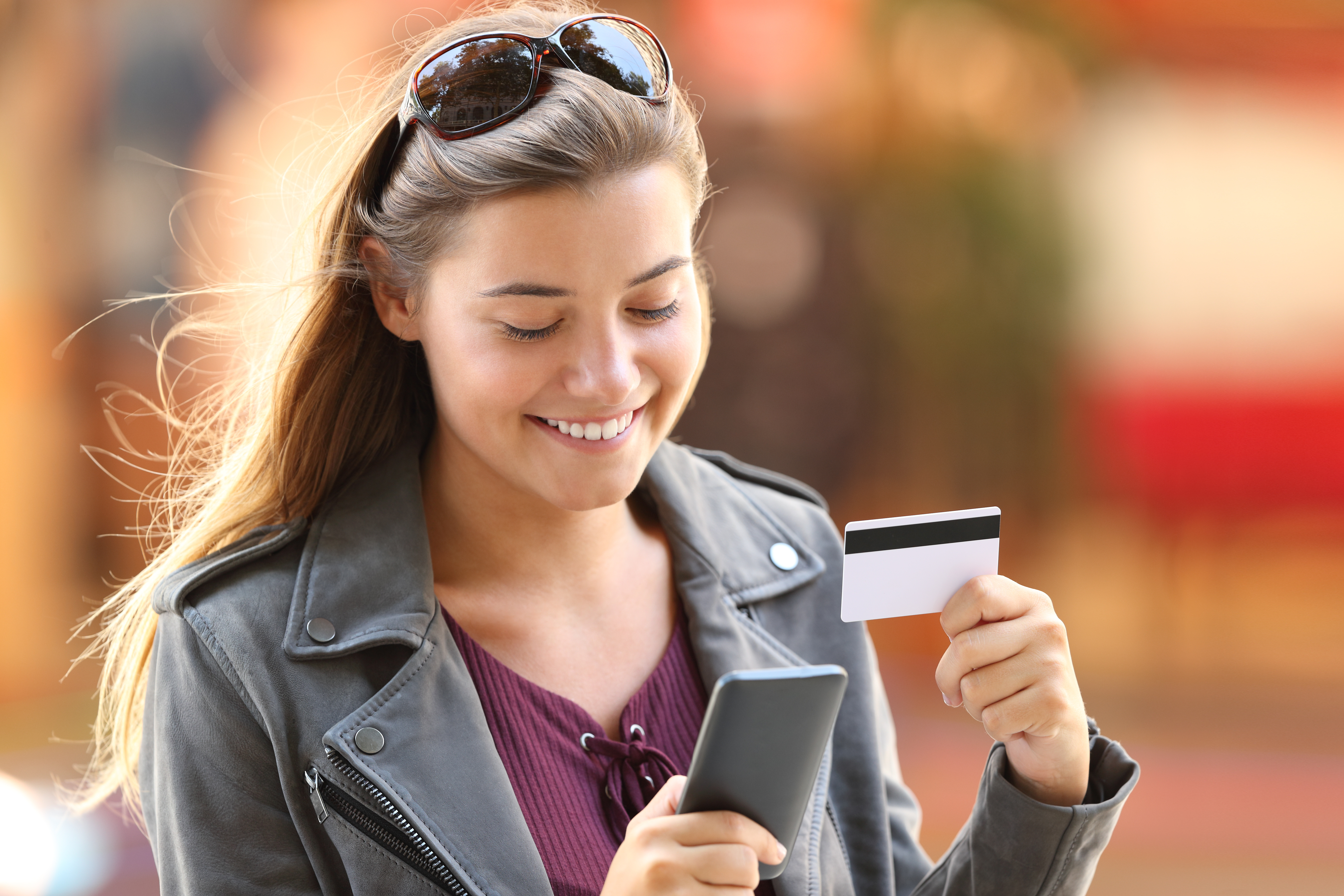 teen girl smiling at phone holding debit card teen girl smiling at phone holding debit card